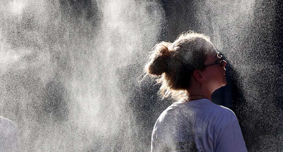 A woman cools off under a mist sprayer during a heatwave in Bordeaux, southwestern France on June 21, 2026. -  Romain Perrocheau, AFP