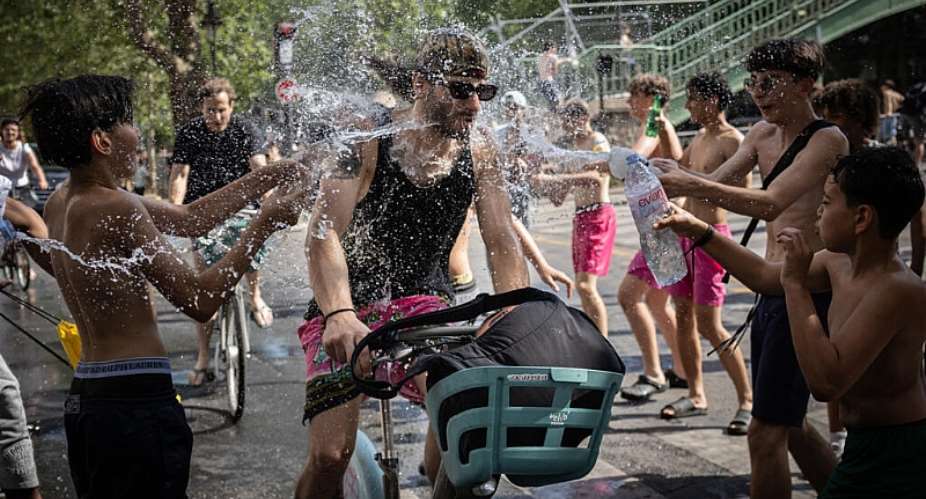 A group of teenagers throw water over a cyclist at the Canal Saint-Martin in Paris, 24 June. - AFP - SIMON WOHLFAHRT