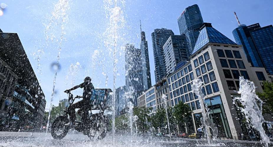 A man rides his bicycle through a fountain outside the banking district in central Frankfurt am Main, western Germany, on June 26, 2026. -  Kirill Kudryavtsev, AFP