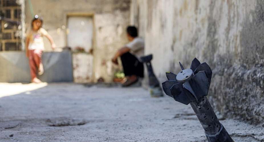 A man speaks with a child while sitting near an unexploded artillery shell that fell during reported overnight Israeli bombardment that hit the village of Abidin in Syrias southwestern Daraa province, close to the Golan Heights, on June 29, 2026. -  AFP, Sam Hariri