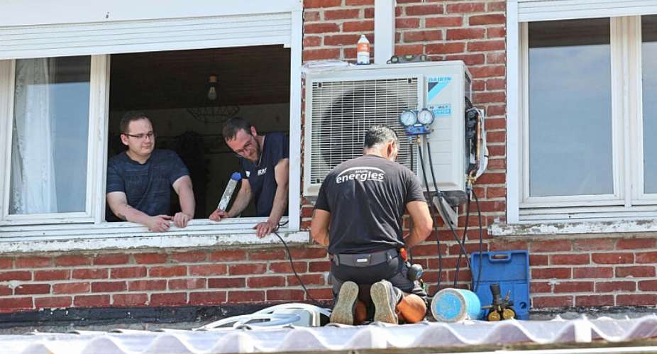 Heating engineers work on installing an air conditioning unit in the home of a local resident (L) in Mericourt, northern France on June 19, 2026. -  Franois Lo Presti, AFP