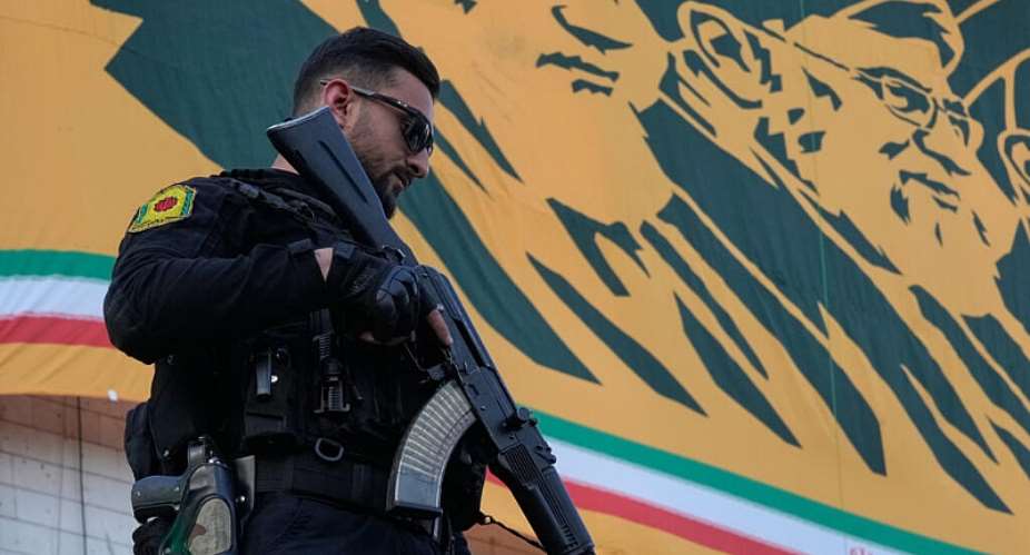 A police officer stands guard near a banner with  portraits of former Iranian leaders Ayatollah Khomeini and Ayatollah Ali Khamenei in Tehran, Iran on April 29, 2026. -  Vahid Salemi, AP