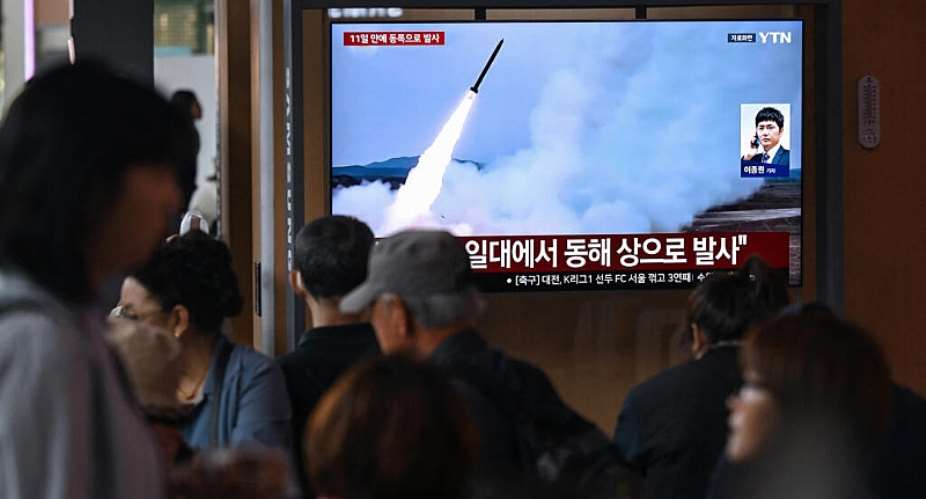 People watch a television screen showing a news broadcast with file footage of a North Korean missile test, at a train station in Seoul on April 19, 2026 -  AFP