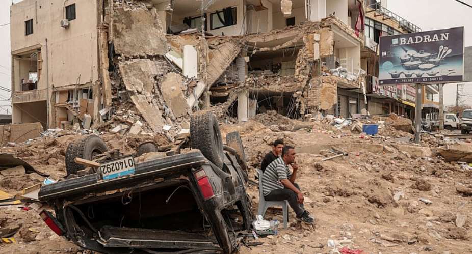 Residents sit amid the rubble of a neighbourhood in the southern Lebanese city of Tyre after an Israeli strike on 18 April 2026. Months of war have displaced more than a million people and deepened political divisions across Lebanon. -  Louisa Gouliamaki / Reuters