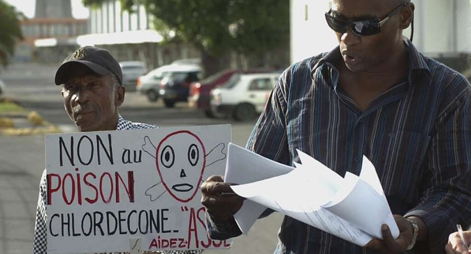 Lawyer Harry Durimel, right, stands beside an activist holding a sign reading No to chlordecone poison during a protest in Les Abymes, Guadeloupe, 18 November 2007. - AP - Dominique Chomereau-Lamotte