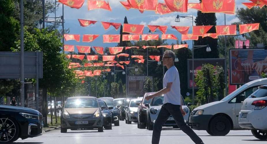 A man walks on a street decorated with national flags in Montenegros capital, Podgorica, on Monday, 18 May 2026. - AP Photo/Risto Bozovic - Risto Bozovic