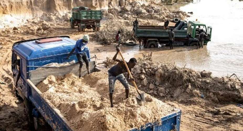 Miners shovel sand into trucks in an area destroyed by sand mining on the outskirts of Gunjur in the Gambia. -  AFP - JOHN WESSELS