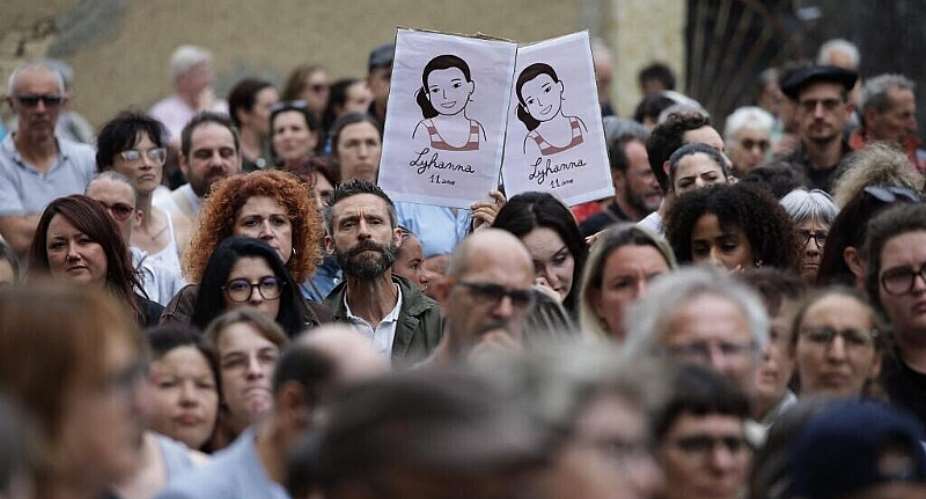 A demonstrator holds placards with an image depicting Lyhanna, an 11-year-old girl found dead on June 4 after being reported missing on May 29 in southwestern France, during a demonstration outside the courthouse at the call of the MouvEnfants collective and other organisations to demand a law against violence on minors, in Auch on 8 June 2026. - AFP - VALENTINE CHAPUIS