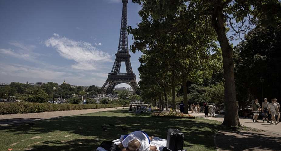 A man sleeps in the shade of a tree near the Eiffel Tower in Paris on July 10, 2026, as a new heatwave hits France. -  Behrouz Mehri, AFP