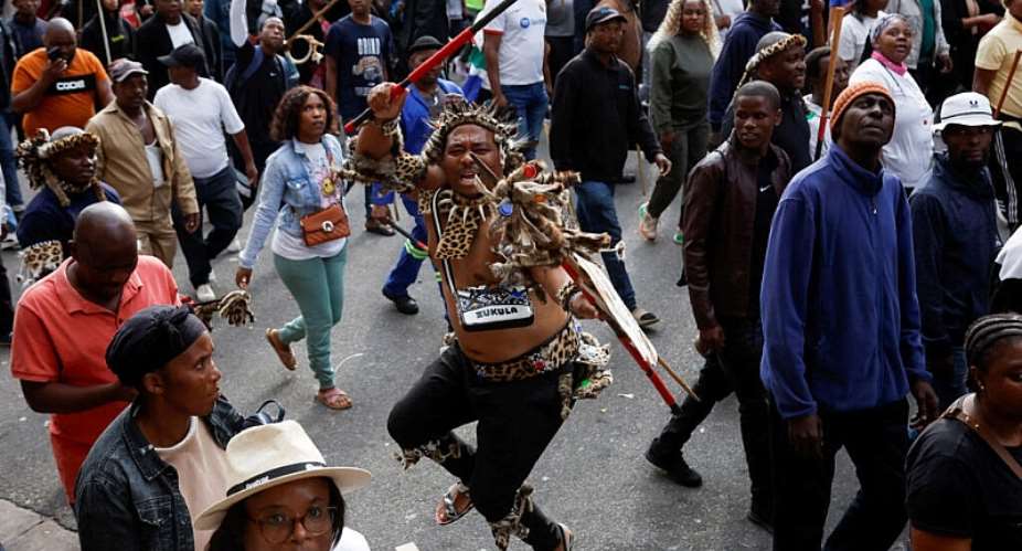 Anti-immigration protesters march through Durban, South Africa, on 30 June 2026, with one demonstrator wearing traditional Zulu attire and carrying a spear as campaign groups marked their unofficial deadline for undocumented migrants to leave the country. -  Rogan Ward / Reuters