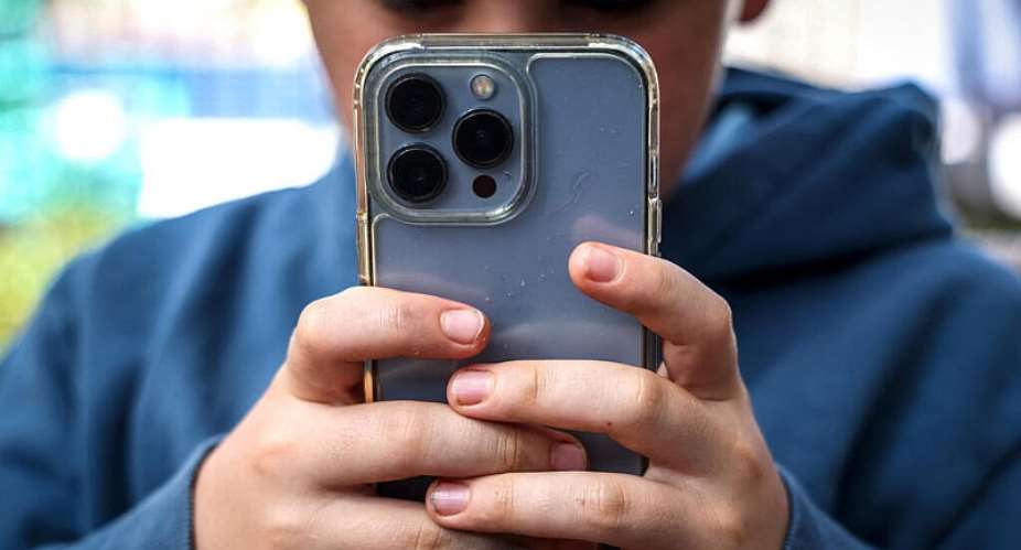 A boy looks at social media on his smartphone. The European Union is weighing how to regulate childrens access to online networks. -  AFP - DAVID GRAY