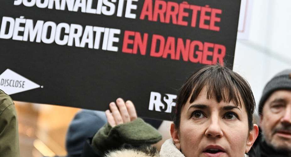 Ariane Lavrilleux delivers a speech before a sign reading Journalist arrested, democracy in danger after she was summoned in January 2025 over the Egypt Papers investigation. - AFP - ANNA KURTH