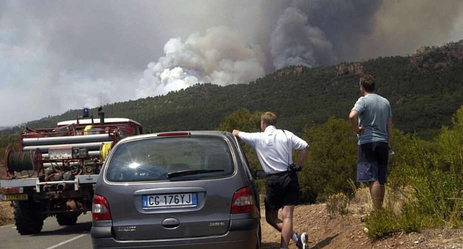 Tourists watch smoke from a forest fire in southern France, July 30, 2003. -  AP