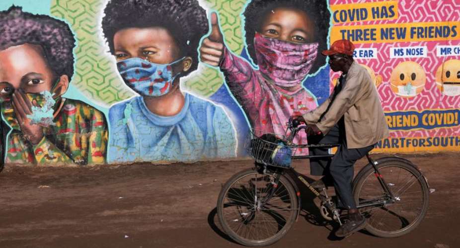 FILE PHOTO: A man rides his bike past a mural by Senzart911 that shows people wearing facemasks, as South Africa scraps isolation for coronavirus disease COVID-19 positive people with no symptoms, at Soweto's Kliptown, South Africa, February 1, 2022. REUTERSSiphiwe Sibeko - REUTERS