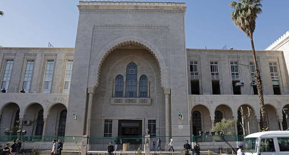 People walk past security personnel standing guard outside the Palace of Justice ahead of the first trial session, in Damascus on April 26, 2026. -  Bakr Alkasem, AFP