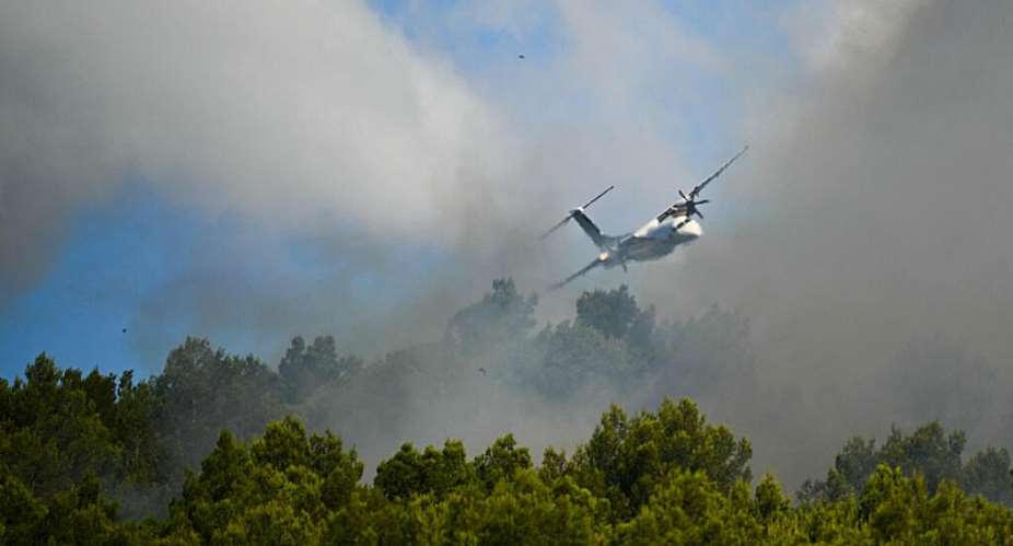 A Dash Fireguard aircraft flies over a wildfire in Pouzols-Minervois, southern France, 2 July. - AFP - LIONEL BONAVENTURE