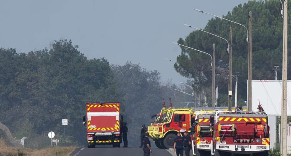 Firefighters stand near the scene where two firefighters died while battling a building fire in Merignac in southwestern France on July 21, 2026. -  Caroline Blumberg, AP
