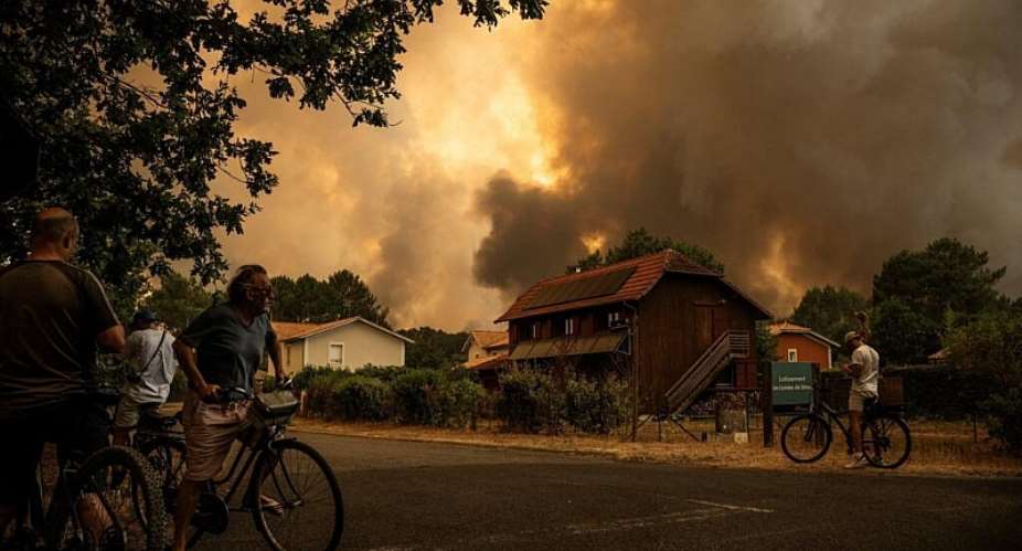 Locals watch as smoke rises behind a residential area during a wildfire near Lege-Cap-Ferret, southwestern France, 23 July. - AFP - JULIEN DE ROSA