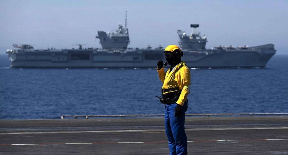 A French marine stands on the bridge of the French aircraft carrier Charles de Gaulle with the UK Royal Navys aircraft carrier HMS Queen Elizabeth in the background during the Navy exercise Gallic strike off the coast of Toulon, southeastern France on June 3, 2021. -  Christophe Simon, AFP