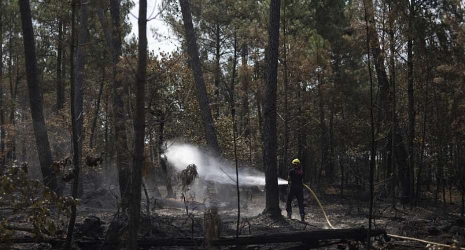 A firefighter puts out residual flames following a wildfire in Andernos-les-Bains, southwestern France on 30 July 2026. - AFP - OLIVIER MORIN