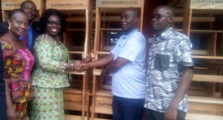 Mr Kena DCE presenting the furniture to Mrs Ivy Owusu Asantewaa, GES District Director