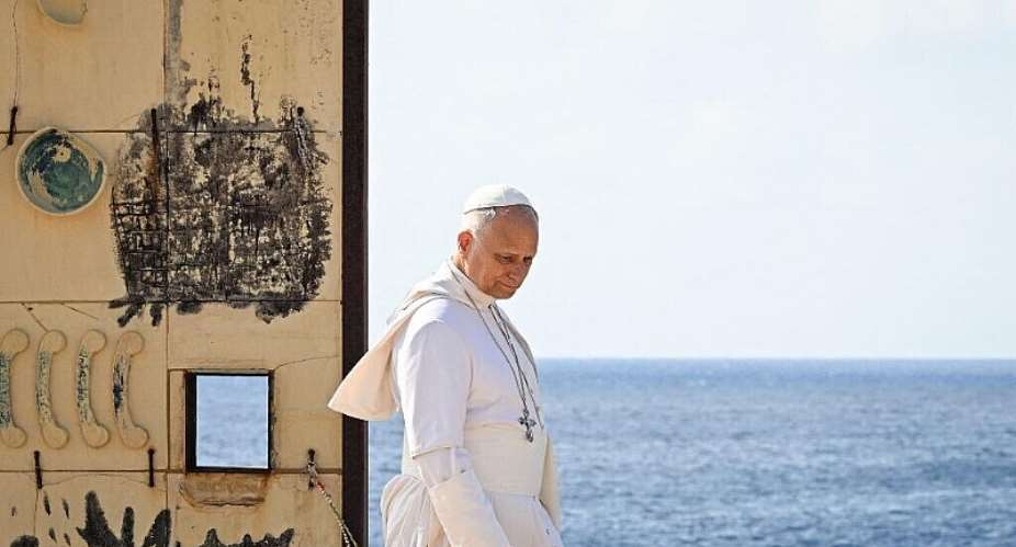 Pope Leo XIV walks through the arch of the Door of Europe monument by Italian artist Mimmo Paladino, during his visit to Lampedusa island on July 4, 2026. - AFP - TIZIANA FABI