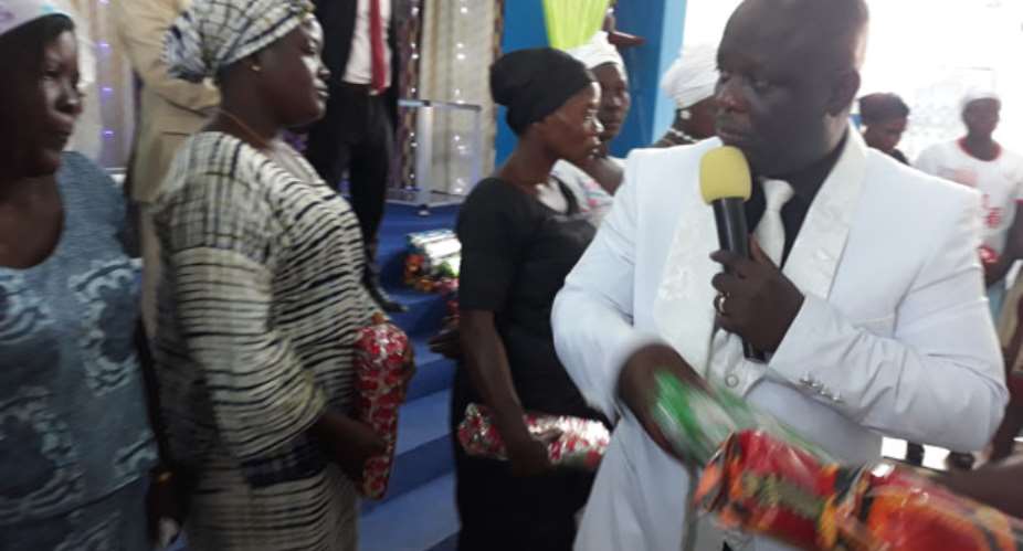 Apostle Kwame Mensah distributing the pieces of cloths to the widows