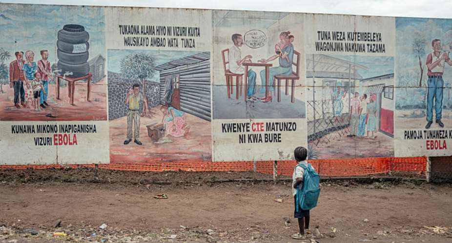 A child returning from school stops to look at Ebola awareness illustrations displayed on the signboards of the Ebola Treatment Center in Munigi on June 2, 2026. -  Jospin Mwisha, AFP