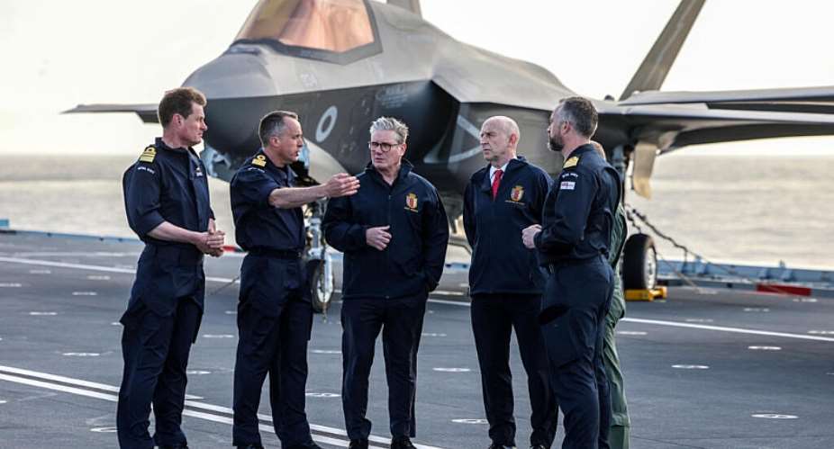 Prime Minister Keir Starmer and other British officials in front of a Royal Navy F-35B Lightning fighter jet on the flight deck of the aircraft carrier HMS Prince of Wales, on 24 April 2025. - AFP - RICHARD POHLE