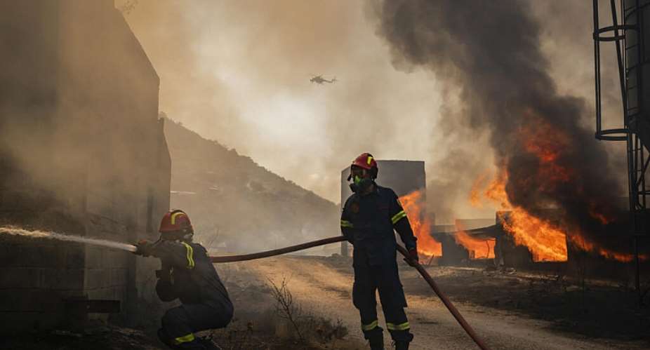 Firemen work to extinguish a blaze that broke out at a livestock facility near Kouvaras, south of Athens, on August 10, 2026 -  Aris MESSINIS / AFP