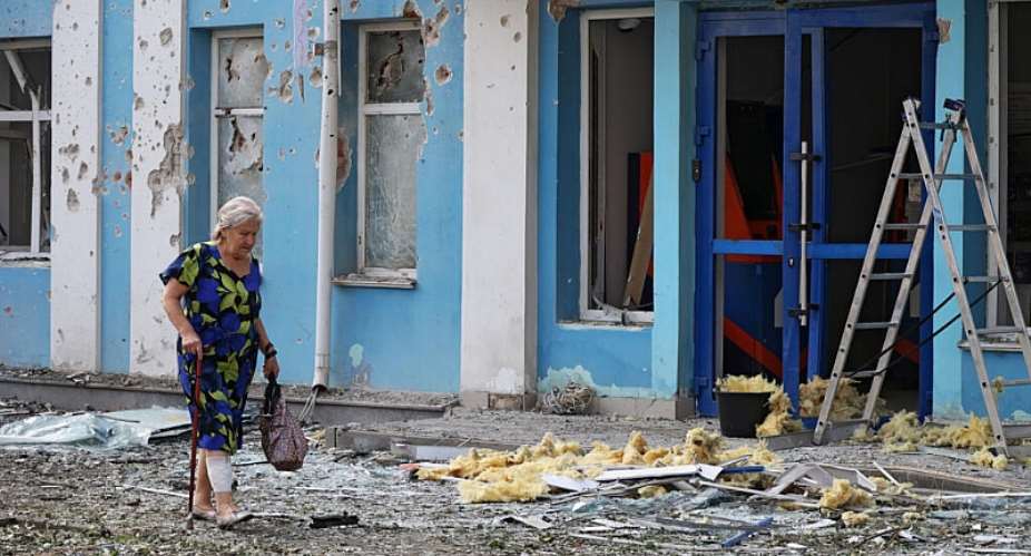 A woman walks past a bank building damaged during a Ukrainian overnight drone attack on Belgorod in Russia on August 9, 2026. -  Stringer, Reuters