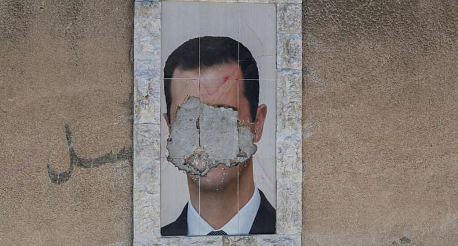 A defaced portrait of Syrias ousted president Bashar al-Assad on a wall in the capital Damascus, 2 June, 2025. - AFP - LOUAI BESHARA