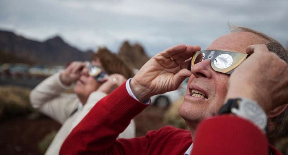 People look at the moon crossing in front of the sun during a partial solar eclipse in Santa Cruz de Tenerife in the Canary Islands, Spain, 3 November, 2013. - AP - Andres Gutierrez