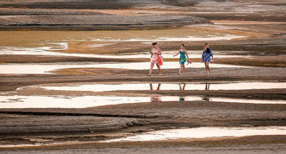 People walk on a sandbank on the Danube River as usually submerged areas are exposed amid exceptionally low water levels, in Rasova, Romania, 7 August. - AP Photo/Andreea Alexandru - Andreea Alexandru
