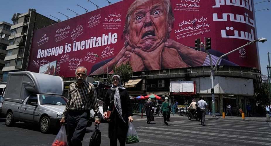 Pedestrians walk past a billboard depicting US President Donald Trump being grabbed by the neck alongside the message Revenge is inevitable in English and Farsi, in Tehran on July 27, 2026. -  Vahid Salemi, AP