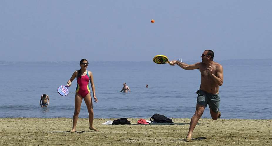 A man and woman play on the beach as other people enjoy the sea during a hot day in southern coastal city of Larnaca on the Mediterranean island of Cyprus, March 31, 2024 -  Petros Karadjias, AP