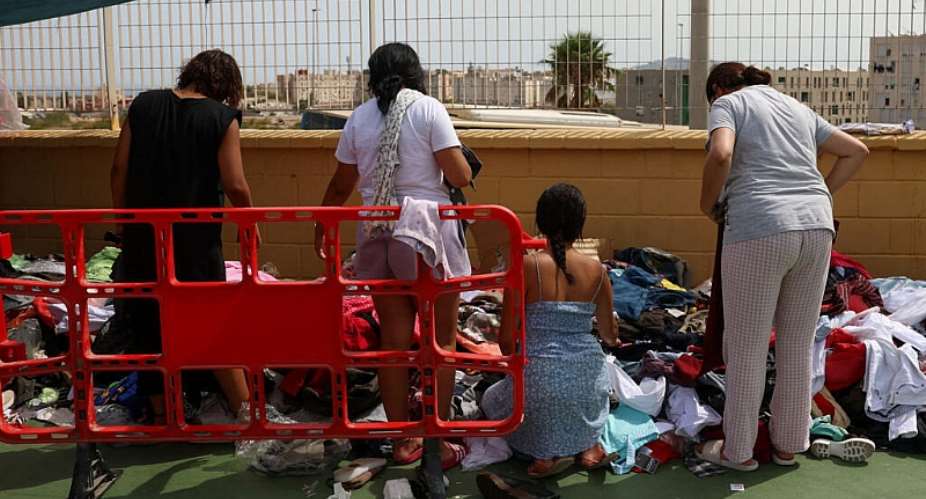 Migrants pick through donated clothes at a sports facility set up by residents as an improvised shelter for women and children, 19 August. -  Violeta Santos Moura/Reuters
