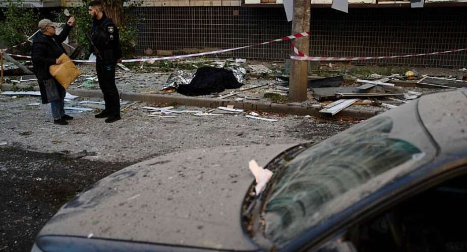 A policeman talks to a local resident next to the bodies of two people killed during an overnight Russian attack in Kyiv on August 20, 2026. -  Francisco Seco, AP Photo