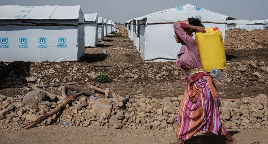 A worker carries a water container at a newly installed internally displaced person camp in Mekele, the capital of Tigray region, Ethiopia. - Source: Photo by Yasuyoshi ChibaAFP via Getty Images