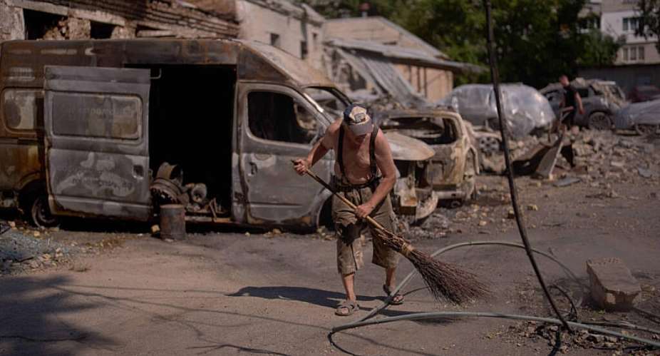A local resident removes scattered debris next to destroyed vehicles the day after a Russian missile and drone attack in Kyiv, Friday, Aug. 21, 2026. -  Francisco Seco, AP