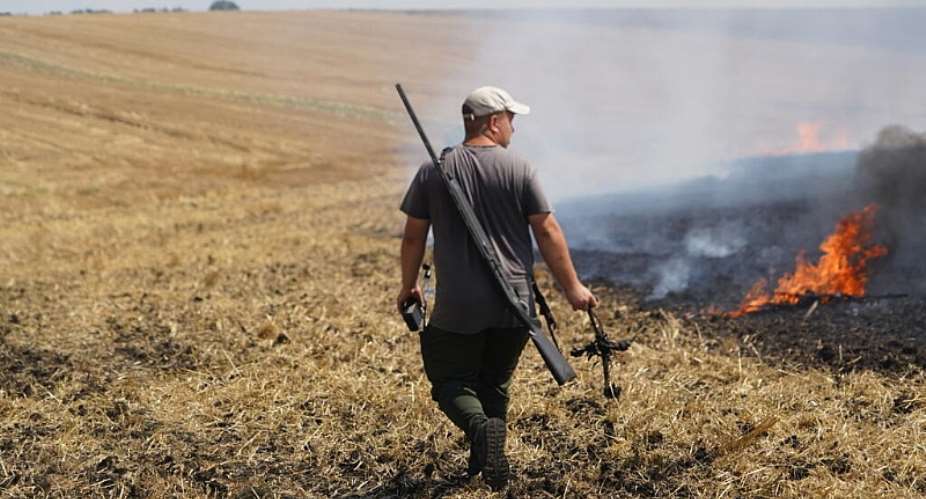 A farmer carries a part of a Russian FPV drone that he shot down with a rifle as he watches a field burn following an air attack in the Kharkiv region, Ukraine, Wednesday, August 5, 2026. -  Andrii Marienko, AP