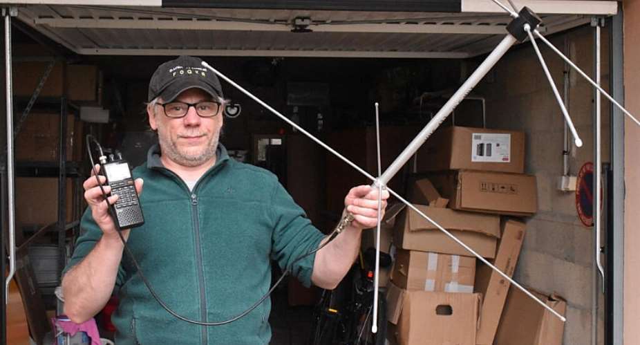 Vincent Plousey, outside his garage in Tavaux, holds a DIY antenna and receiver that allow him to listen in on passing satellites. -  Baptiste Coulon / RFI