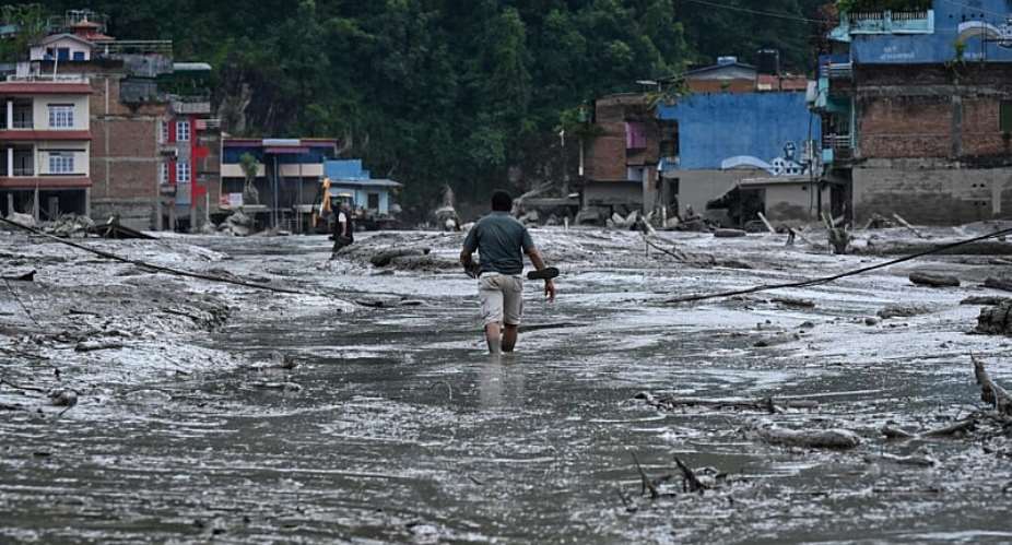 A resident walks down a street flooded with mud in Devighat, in Nepals Nuwakot District, on August 26, 2026. -  Prakash Mathema, AFP