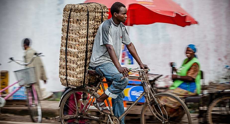 A man rides a bicycle on a market road in Dar es Salaam, Tanzania. Image by Oxford Media Library
