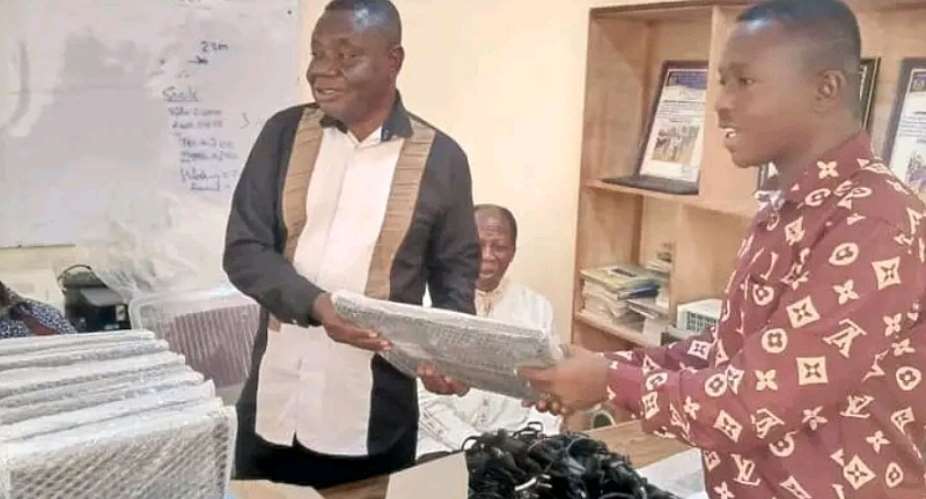 Mr Frank Ayim Damptey presents 20 laptops to the Headmaster of Presbyterian Primary School, Mr Alex Misah. Looking on are Mr Daniel Danquah Damptey, Mr William Gyasi Damptey, the Resident Minister, the Catechist, and the Senior Presbyter during the presentation ceremony.