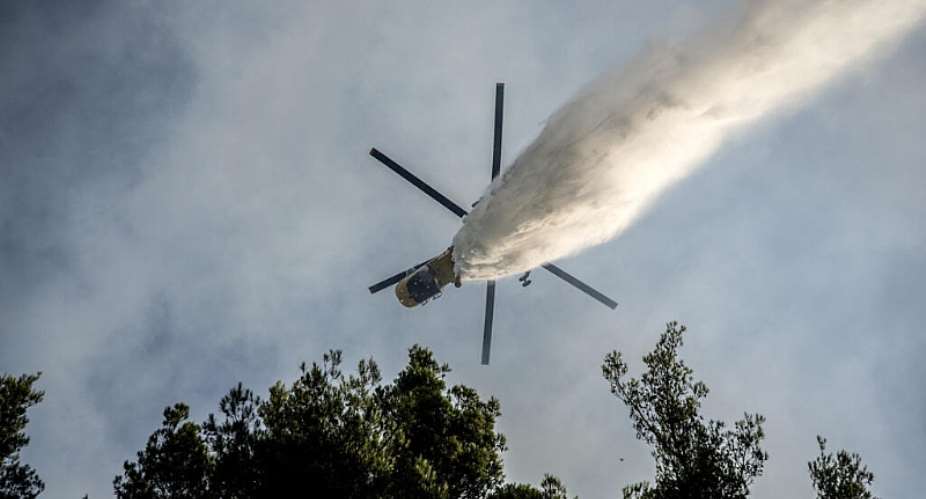 A firefighting helicopter drops water over a wildfire in the area of Porto Germeno, some 70 kilometres northwest of Athens in the region of Viotia, on 2 August 2026. - AFP - ANGELOS TZORTZINIS