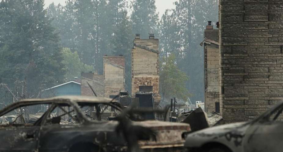 Debris is strewn around burned structures after a wildfire, Sunday, Aug. 2, 2026, in Spokane, Wash -  Young Kwak, AP