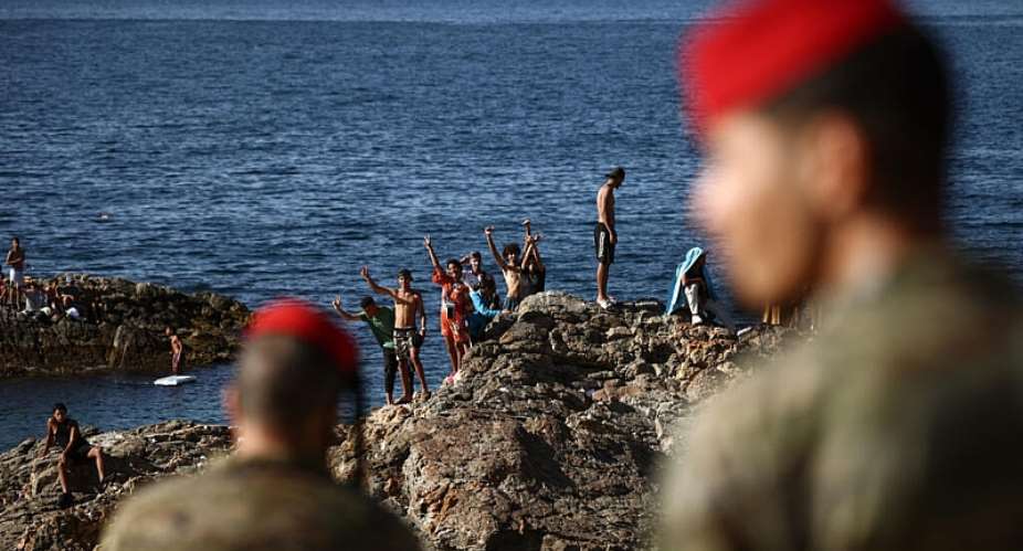 Members of the Spanish Armys Regulares infantry forces watch a group of migrants near the border post of the Spanish enclave of Ceuta on 2 August 2026. - AFP - HENRY NICHOLLS
