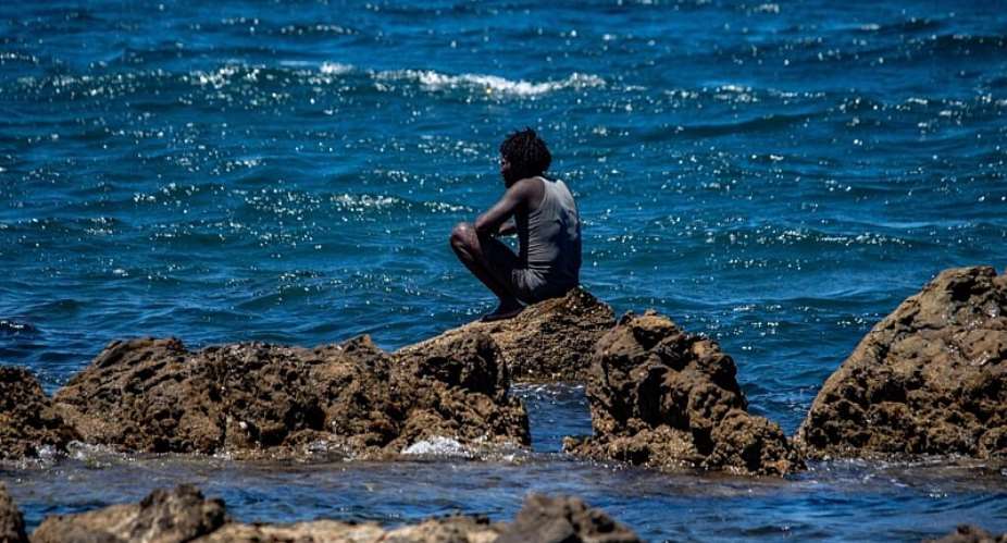 A migrant who crossed into Spain from Morocco sits on a shore in the Spanish enclave of Ceuta, Sunday, Aug. 2, 2026. -  Antonio Sempere, AP