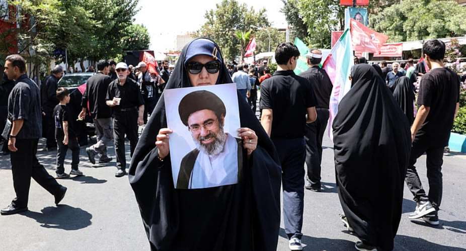 An Iranian woman holds a portrait of Iranian supreme leader Ayatollah Mojtaba Khamenei as Shia Muslim devotees take part in a mourning procession marking Arbaeen in Tehran on August 4, 2026. -  AFP